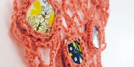 Close up of pink crochet sculpture with pieces of a French children's game