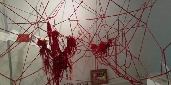 A large 3d red wool installation with crochet chains, tangles and drawings